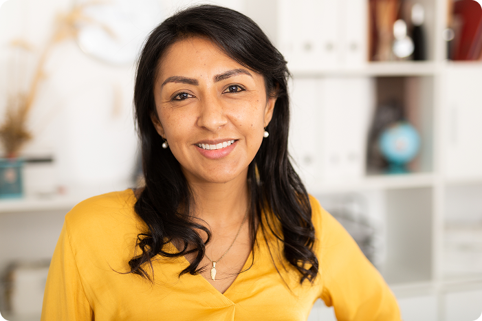 Woman in a yellow top smiling warmly in an office setting