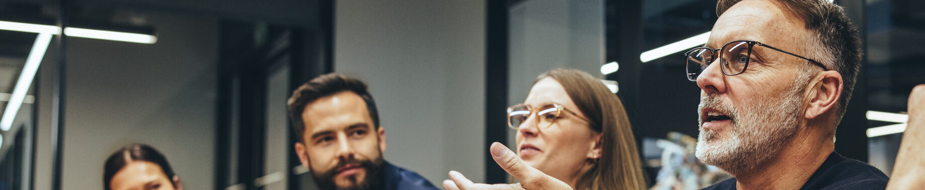 Meeting discussion, four people engaged, one speaking with expressive gestures