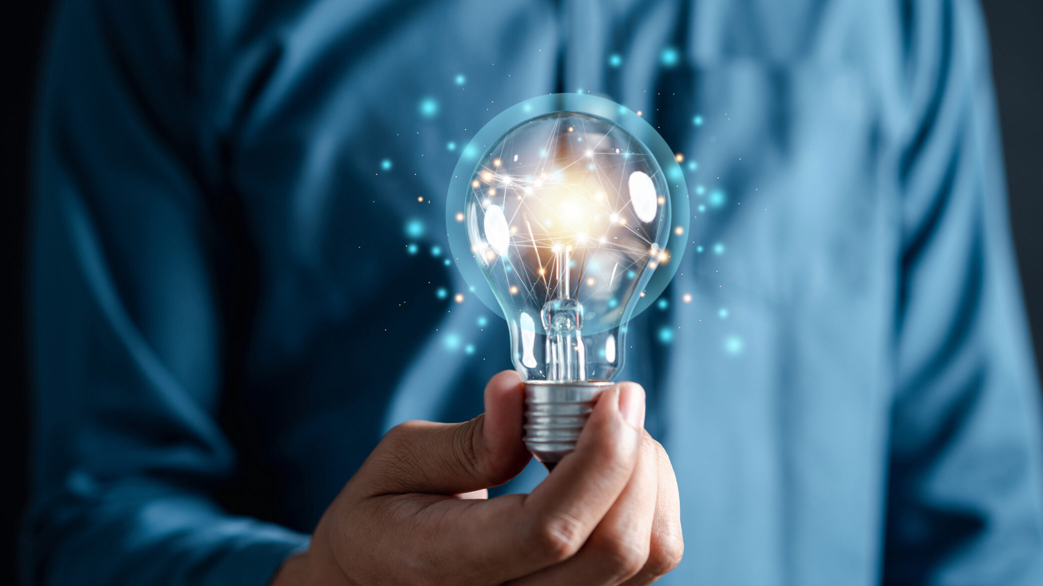 Hand holding glowing light bulb with interconnected blue dots