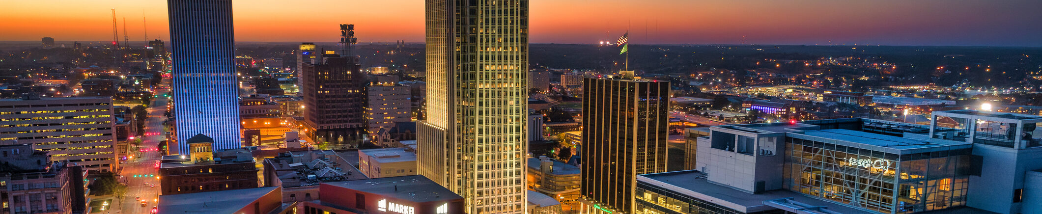 City skyline at sunset with illuminated buildings and distant horizon