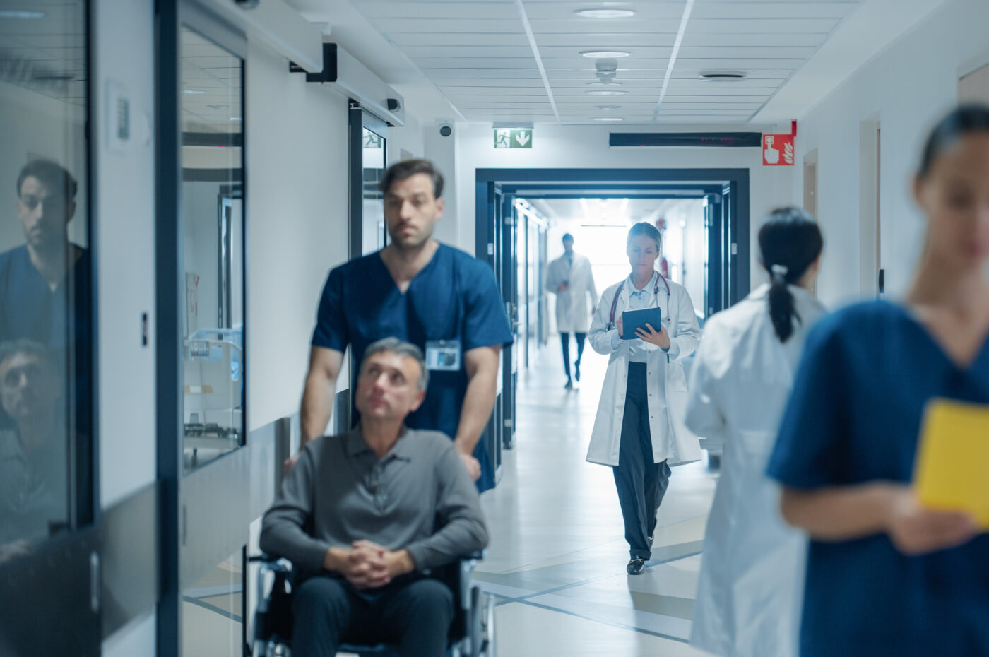 Hospital corridor scene with staff and patient in wheelchair