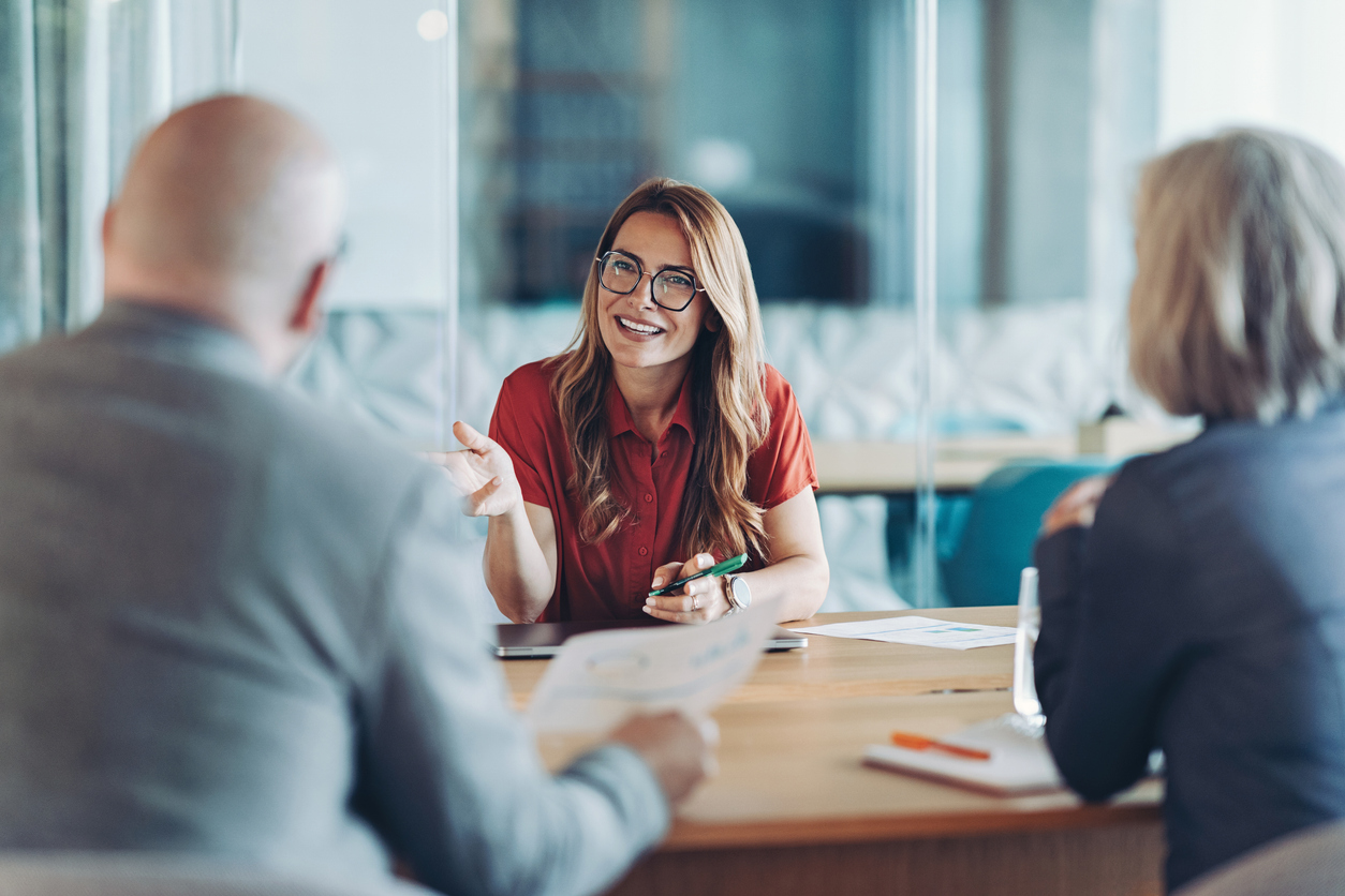 Woman in red shirt smiling during a business meeting with two other people