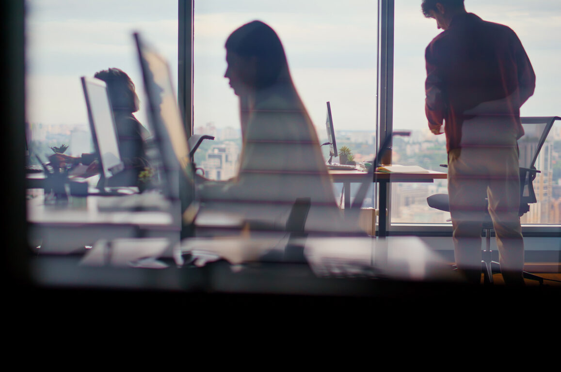Silhouettes of people working in a modern office with city view