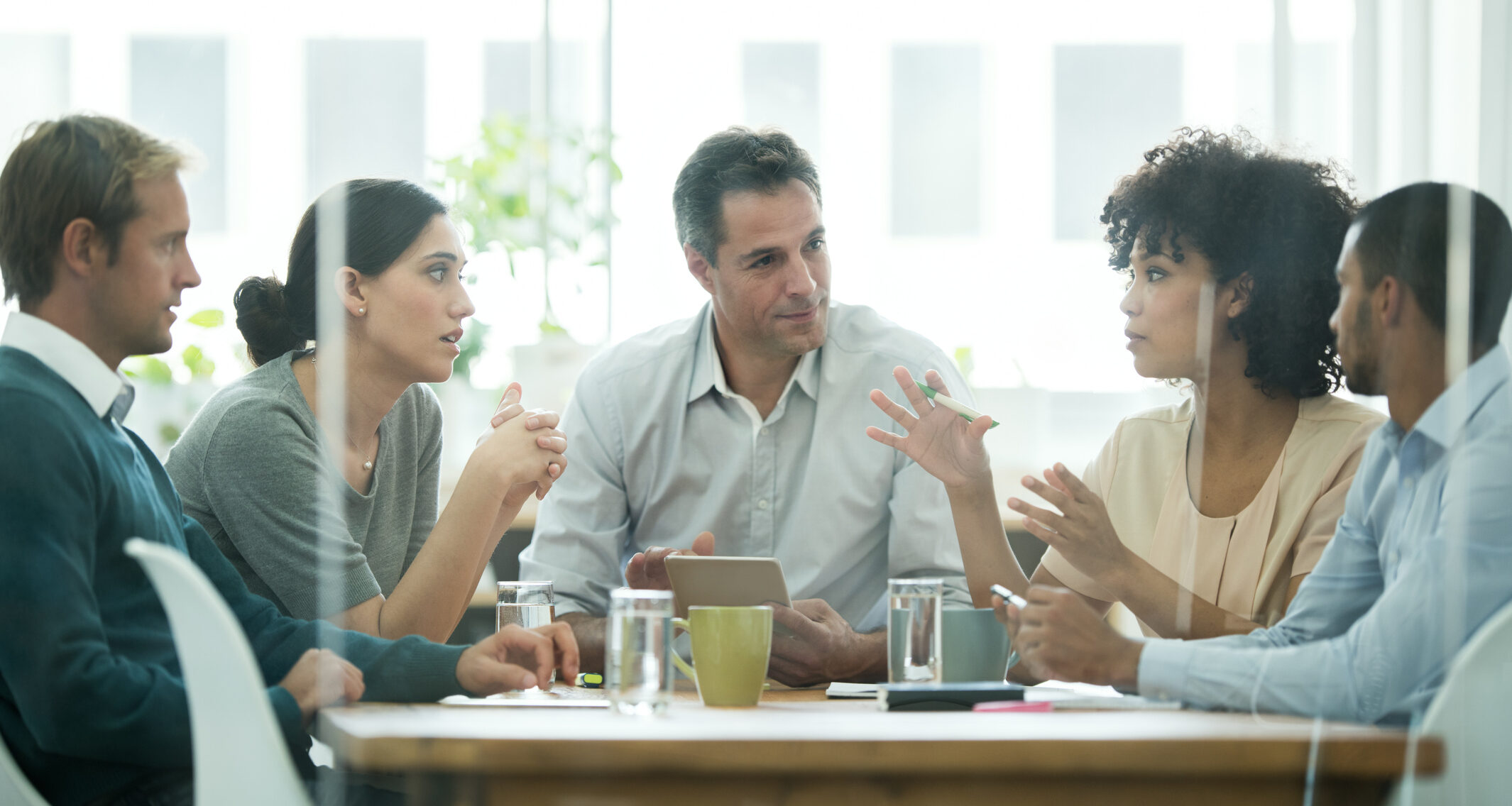 Diverse group in a meeting discussing ideas animatedly around a table