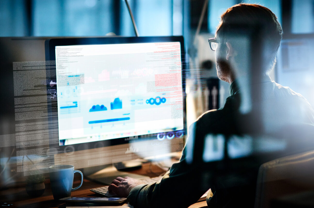 Person analyzing data on a large computer screen displaying graphs